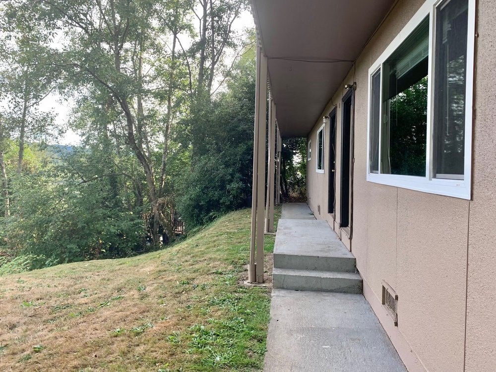 the side of a building with a sidewalk and trees