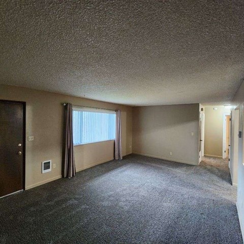 an empty living room with a window and a door
