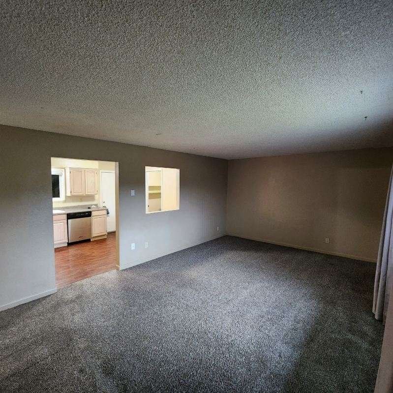 an empty living room with a kitchen in it