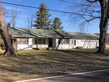 a small white house with a yard and trees