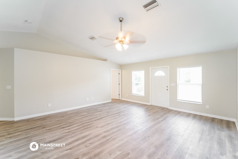 an empty living room with white walls and a ceiling fan