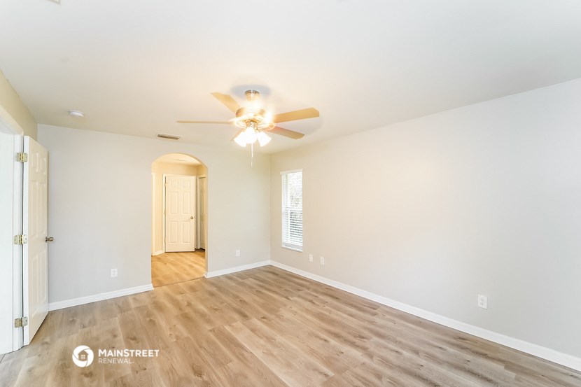 the spacious living room with wood flooring and ceiling fan