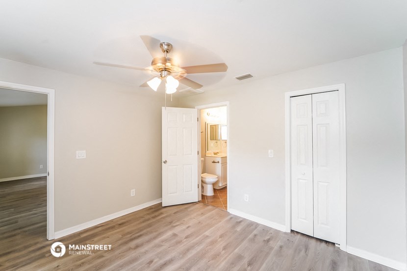 a living room with a ceiling fan and a door to a bathroom