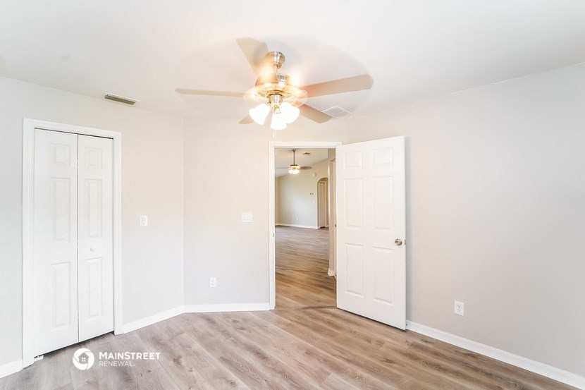 a living room with a ceiling fan and a hallway