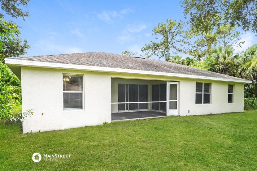 a small white house with a lawn and a screened in porch
