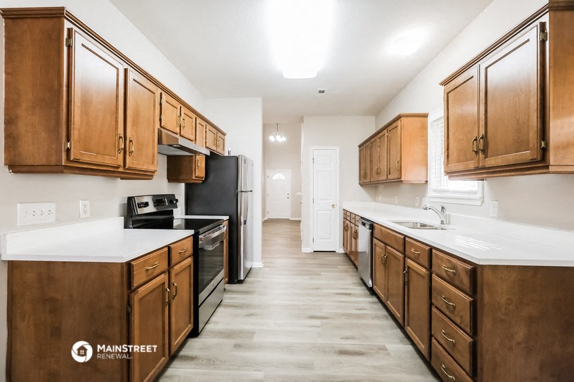 a kitchen with wood cabinets and white counter tops and a black stove and refrigerator