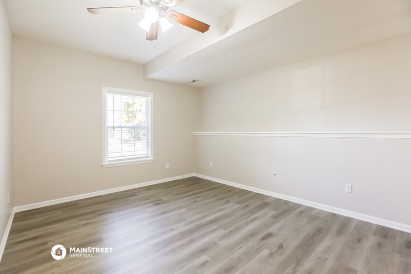 the spacious living room with hardwood flooring and a ceiling fan