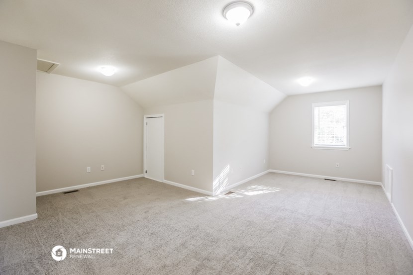 the spacious living room with carpeting and a window