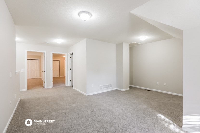 the spacious living room and dining room with white walls and carpet