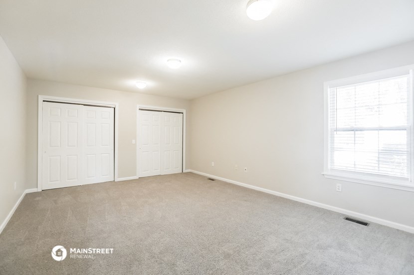 the spacious living room with two closets and two windows