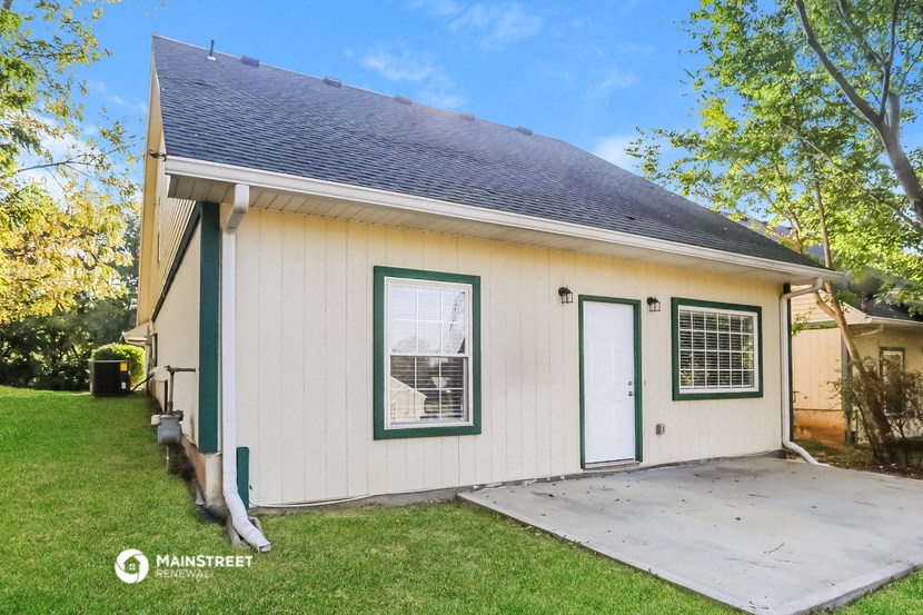 the backyard of a small white house with a porch and a door