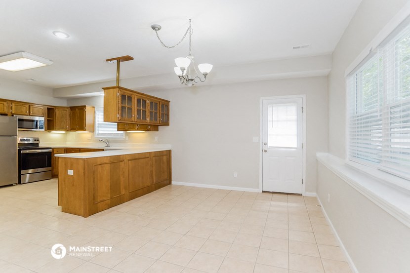 an empty kitchen with wooden cabinets and a window