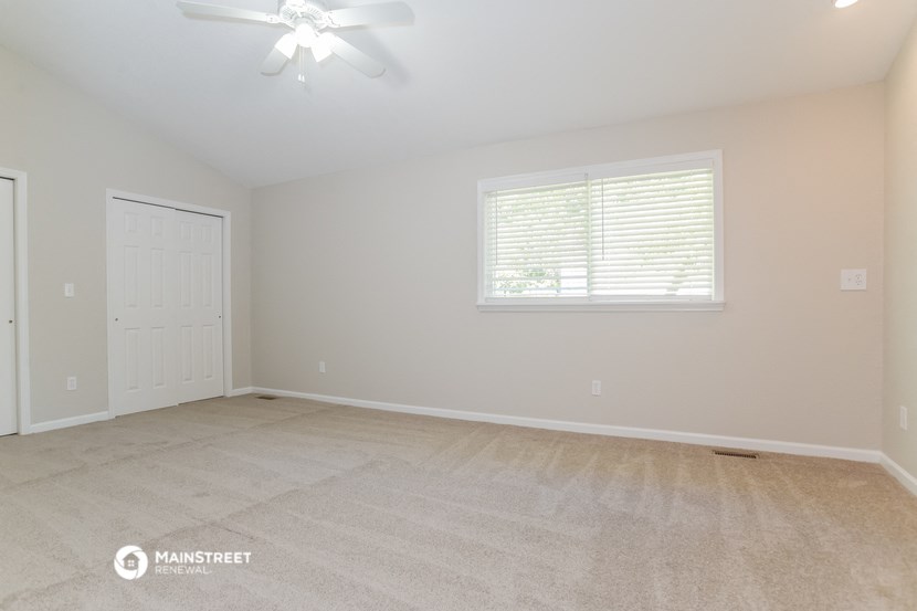 the spacious living room with carpeted flooring and a window