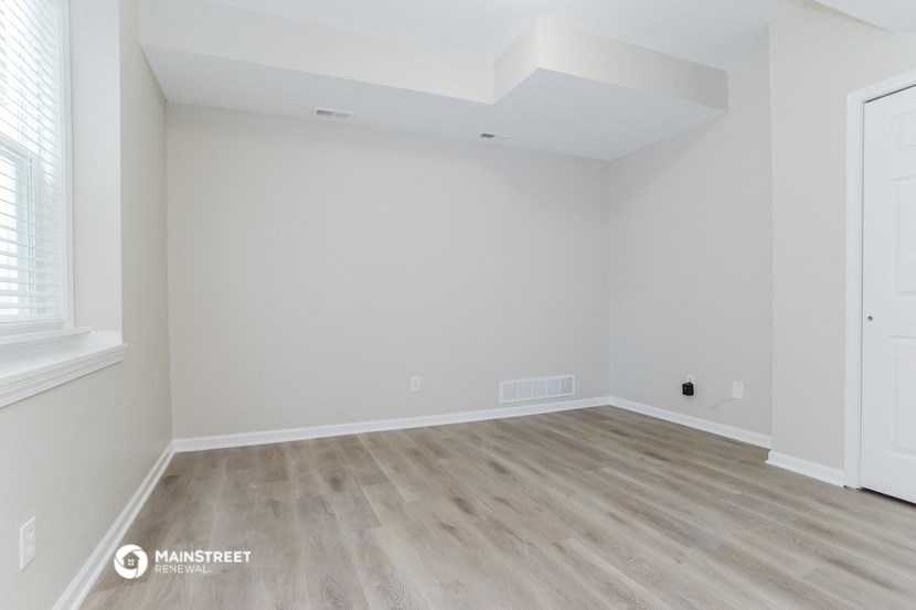 an empty room with white walls and wood flooring