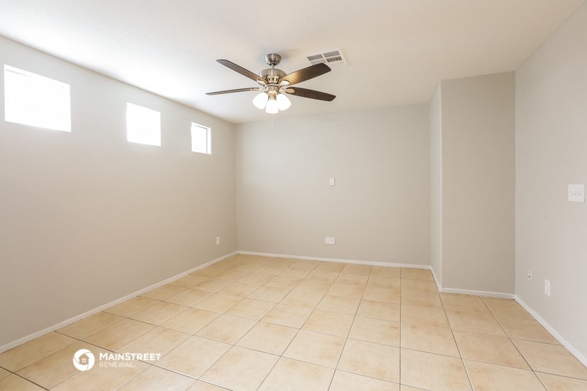 a empty living room with a ceiling fan and a tiled floor