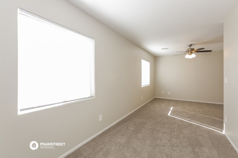 an empty living room with a ceiling fan and a large window
