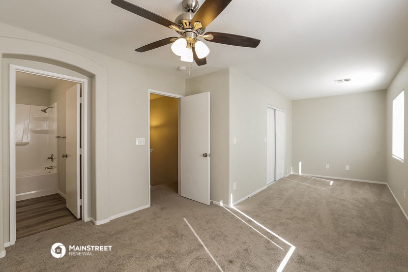 a empty living room with a ceiling fan and a closet