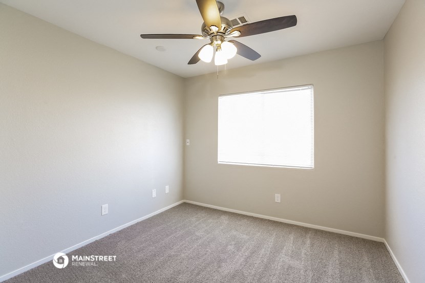 an empty room with a ceiling fan and a window