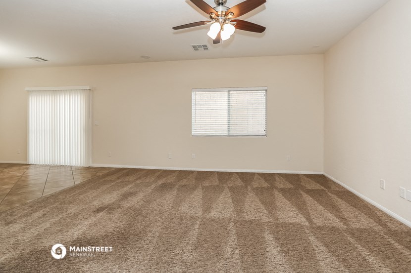 the spacious living room with ceiling fan and carpet