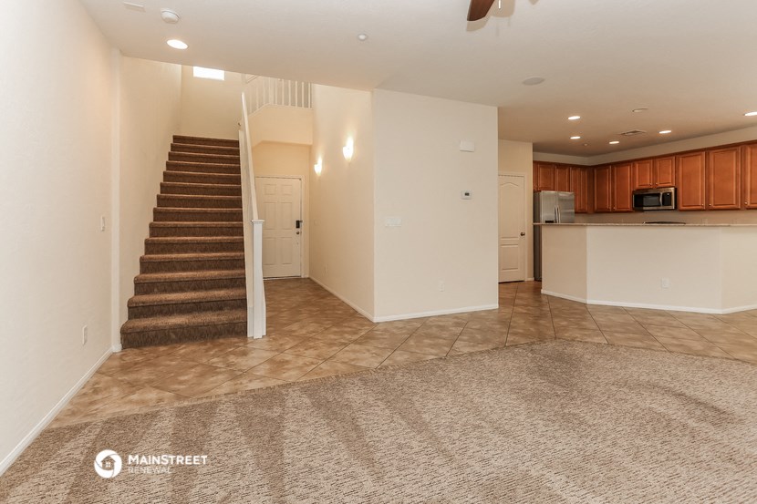 an empty living room with a staircase and a kitchen