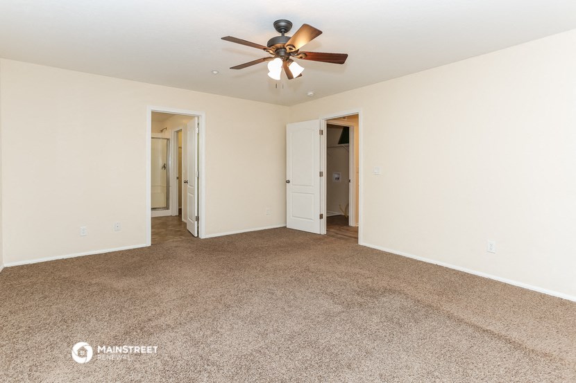 a living room with carpet and a ceiling fan