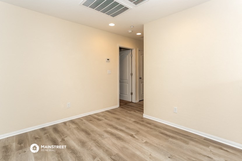 the living room of a house with wooden floors and white walls