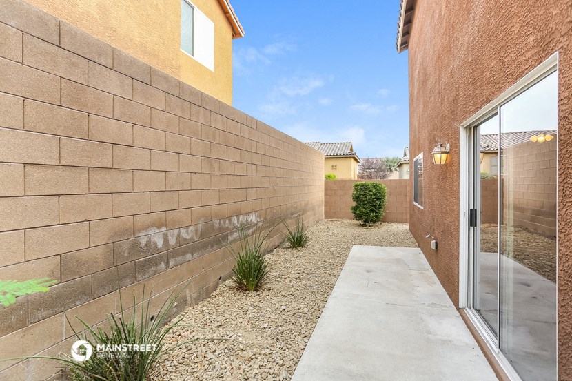 a concrete walkway next to a brick wall with a glass door