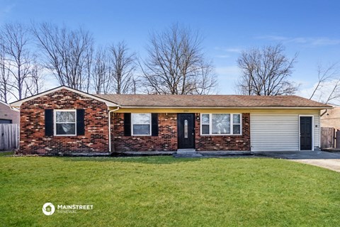 a small brick house with a yard in front of it