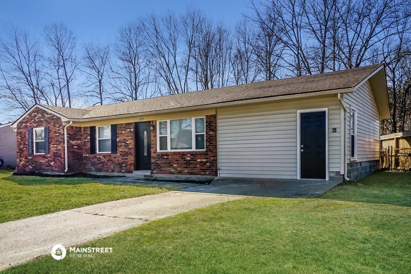 the front of a brick house with a driveway and grass