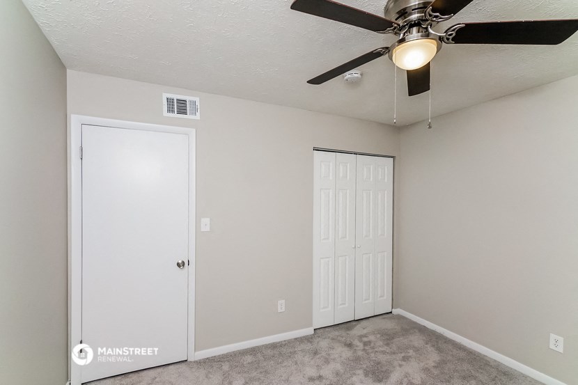 a bedroom with a ceiling fan and a closet