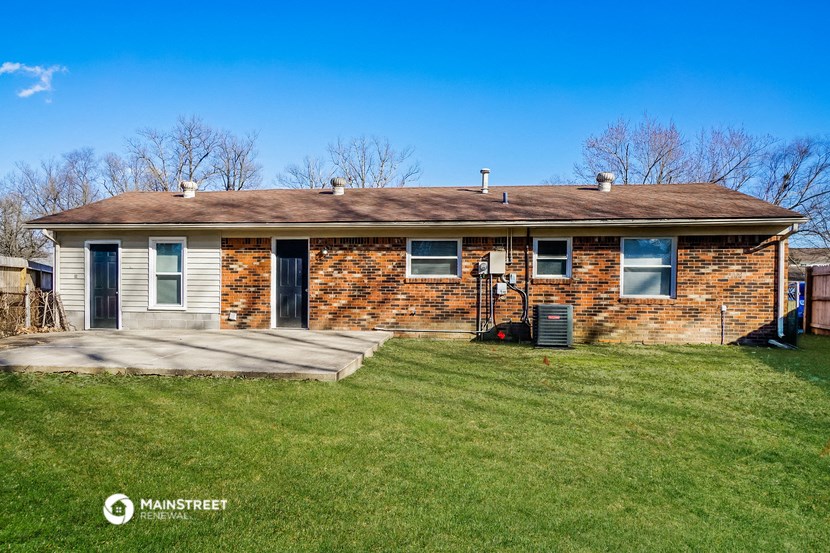 a small brick house with a porch and a lawn