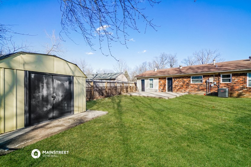 a backyard with a greenhouse and a shed and a brick house