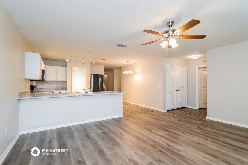 a living room with a kitchen and a ceiling fan