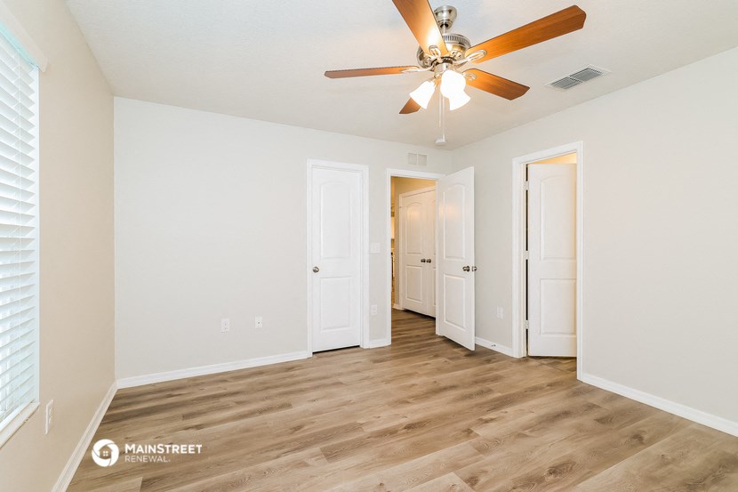 a spacious living room with white walls and a ceiling fan