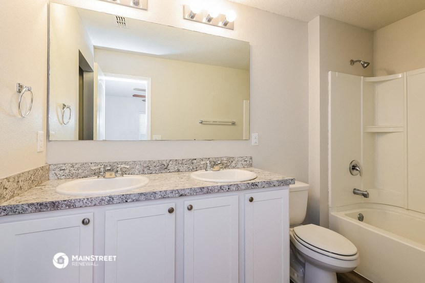 a bathroom with two sinks and a toilet and a mirror