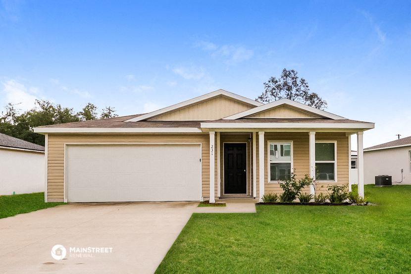 a beige house with a lawn and a driveway