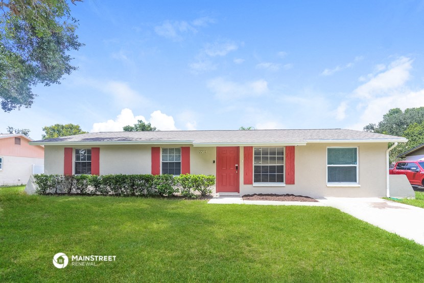 a white house with red doors and a lawn