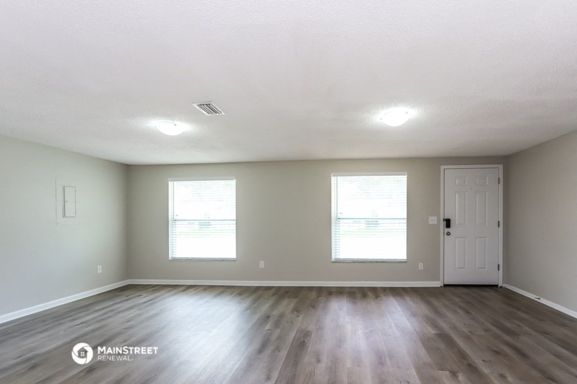 the spacious living room with hardwood floors and a white door