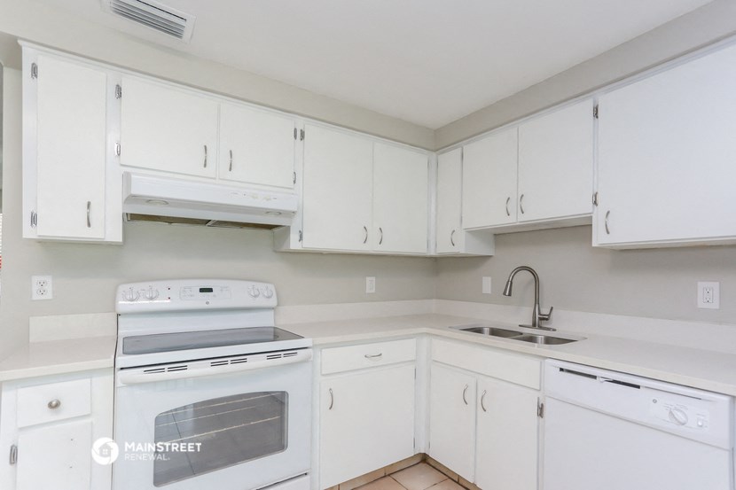 a kitchen with white cabinets and white appliances and a sink