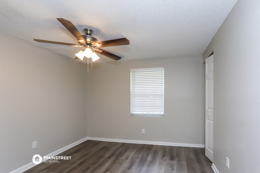 the spacious living room with ceiling fan and wood flooring