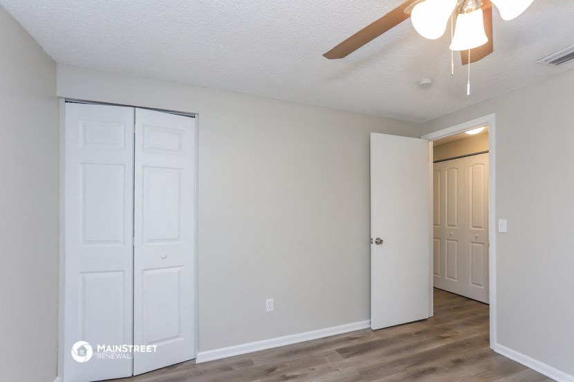 the living room of an apartment with white doors and a ceiling fan