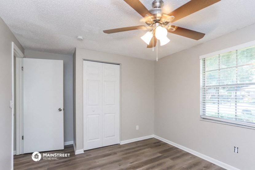 an empty bedroom with a ceiling fan and a door