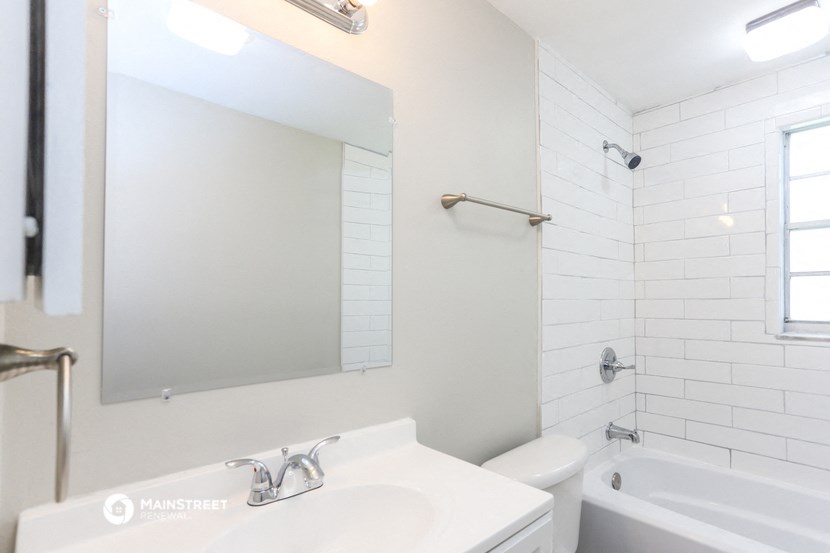 a bathroom with a sink and a mirror and a tub and a toilet