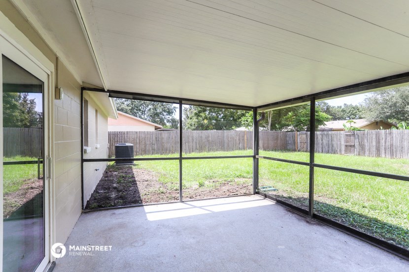 a patio in a screened in porch with glass doors and a backyard