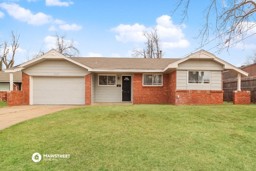 the front of a brick house with a lawn and a driveway