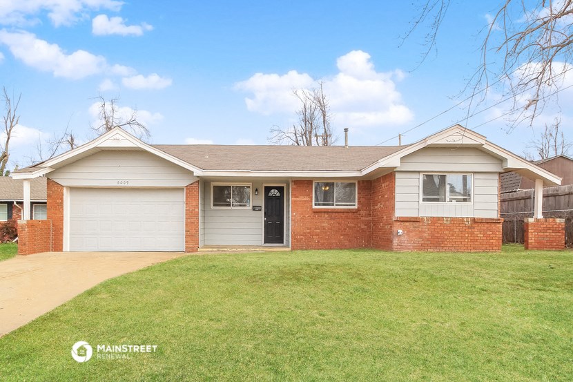 a brick house with a green lawn and a driveway