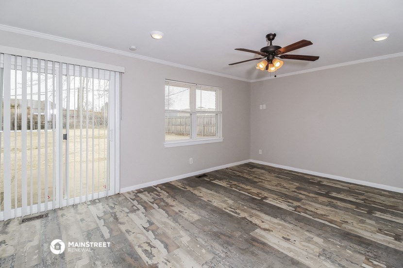 the living room of a home with a ceiling fan and sliding glass doors