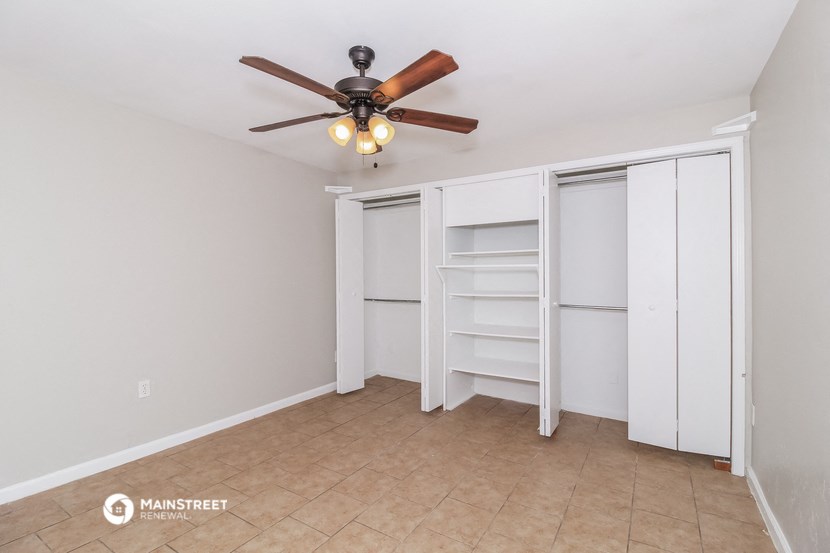 a bedroom with a ceiling fan and a closet with shelves