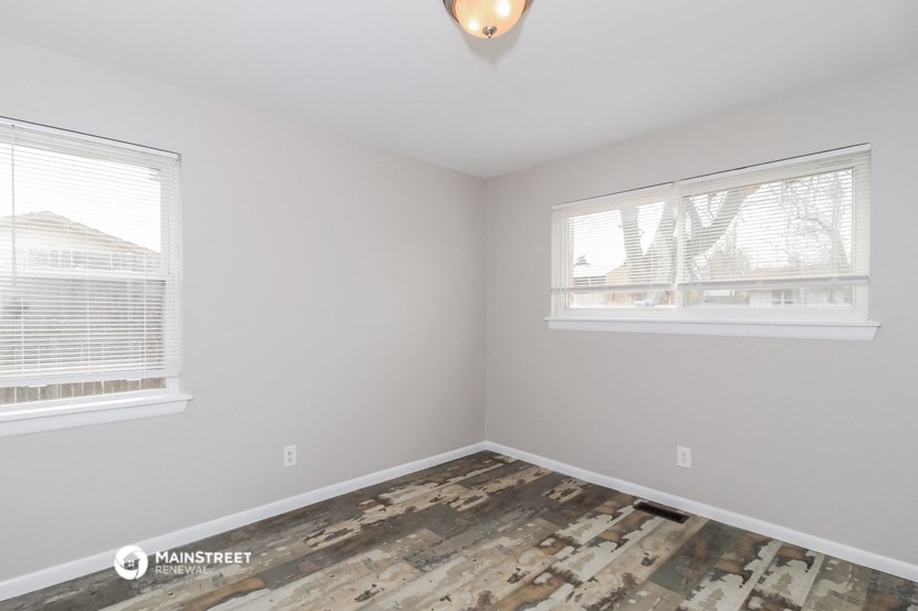 the living room with wood flooring and two windows