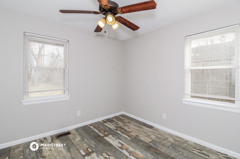the bedroom has a ceiling fan and two windows